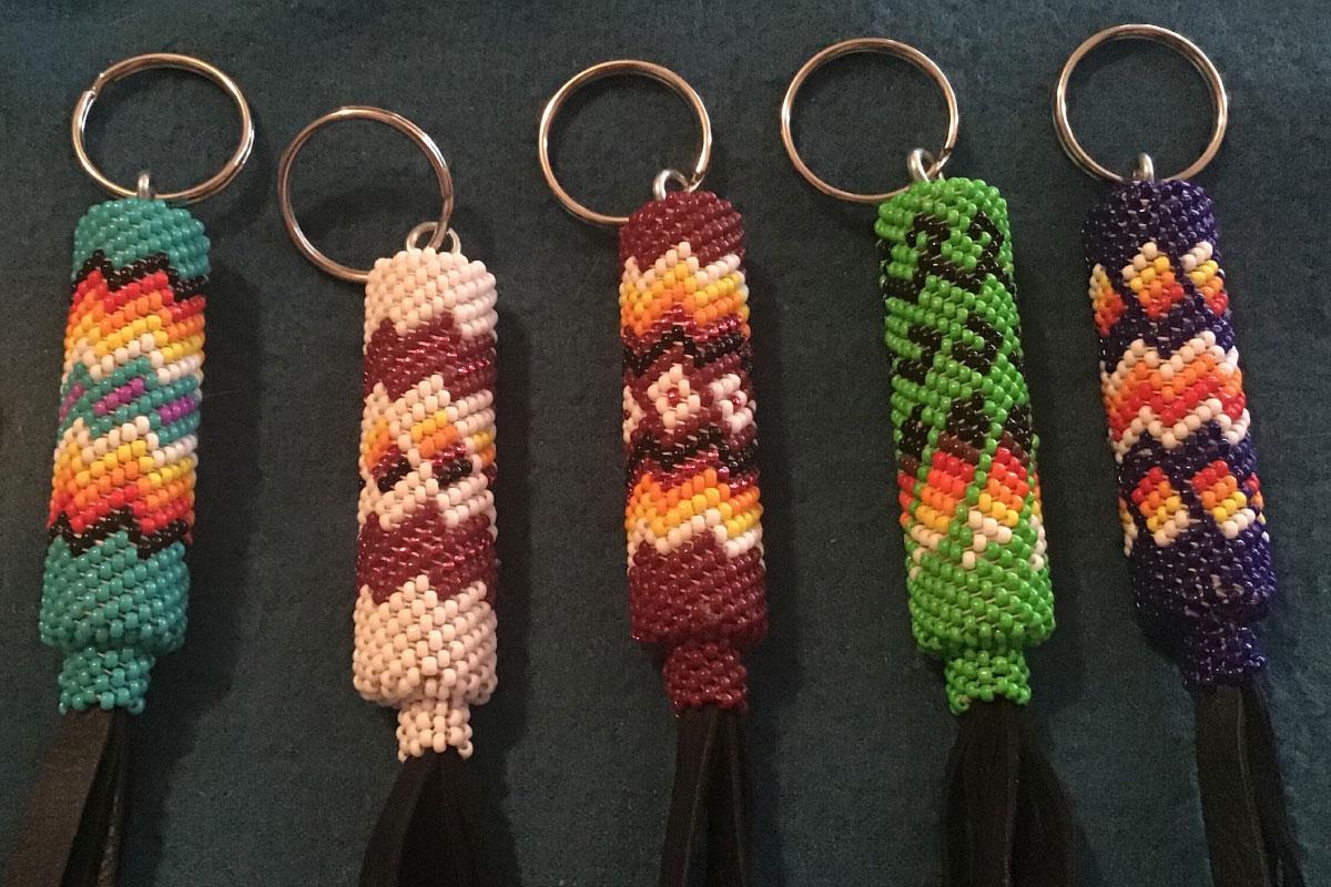 Five keychains with traditional Native American beadwork in greens, orange, red, pink with tassels